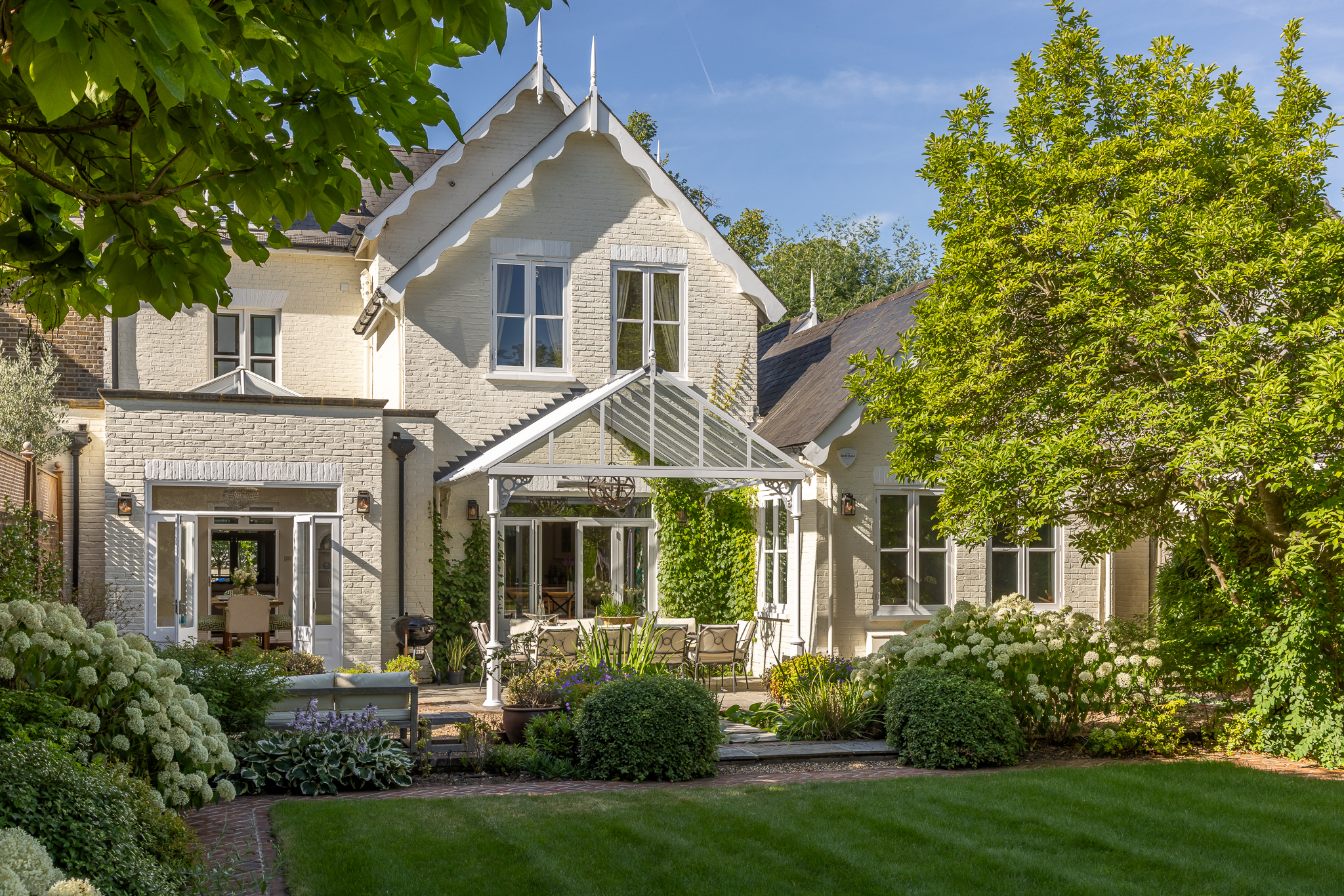 A bespoke Orangery set within a considered garden design, framed by layered planting and connected to the main home through a strong visual axis